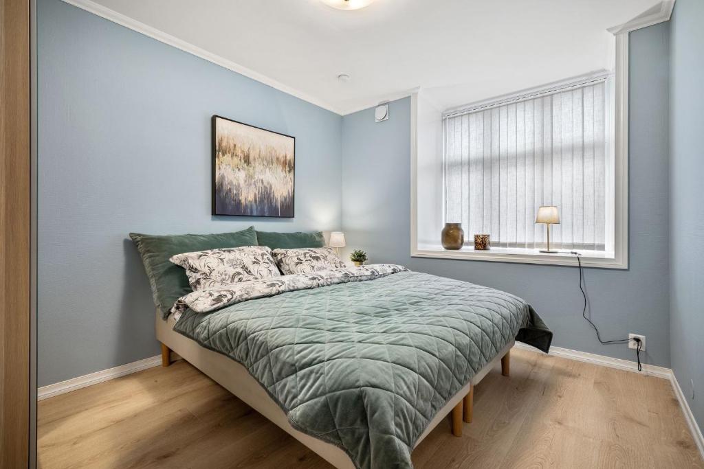 a bedroom with a bed with a green comforter and a window at Holmboe Apartment in Bergen