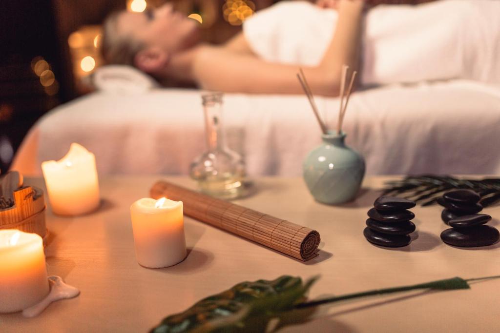 a table with candles and a man sleeping in a bed at Dukley Hotel & Resort in Budva