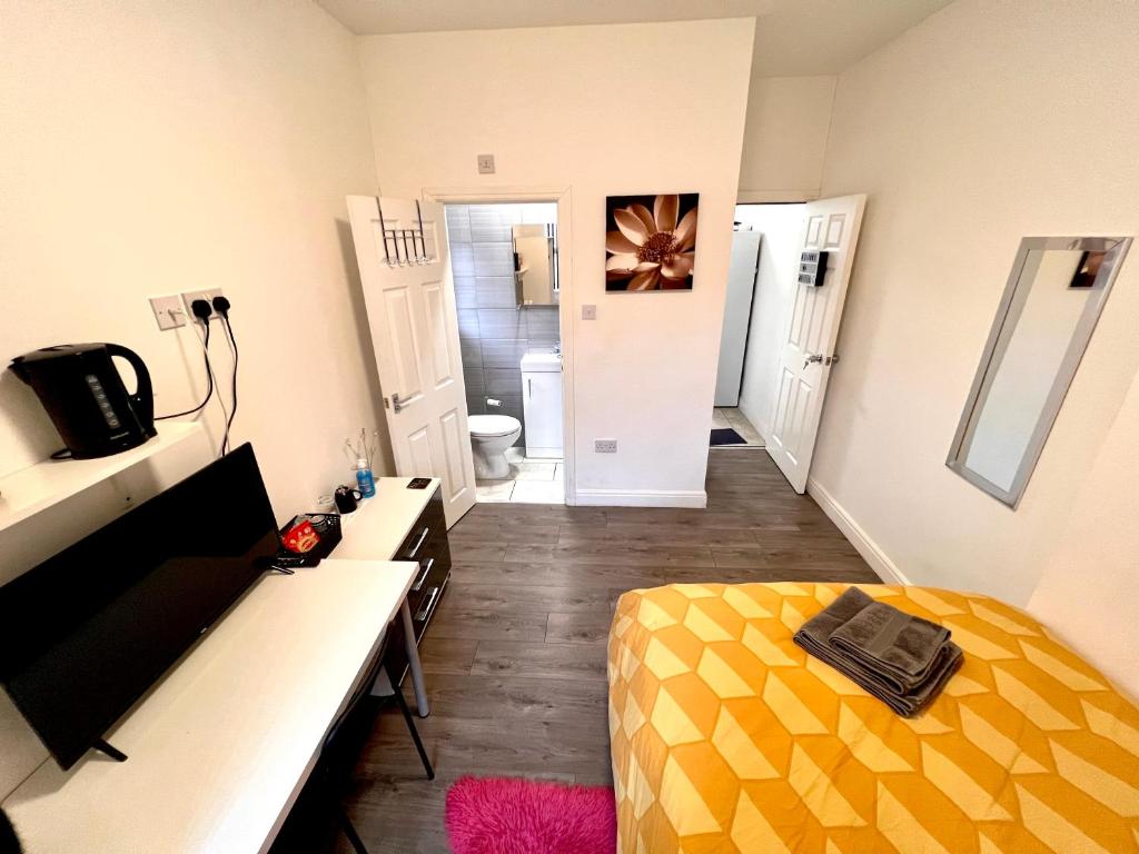 a bedroom with a yellow bed and a bathroom at Deluxe En-suite room in CV1 in Coventry
