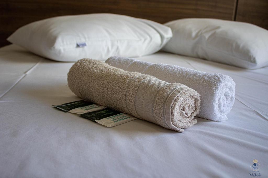 uma toalha enrolada numa cama com duas almofadas em Pousada Bela Rainha em Aparecida