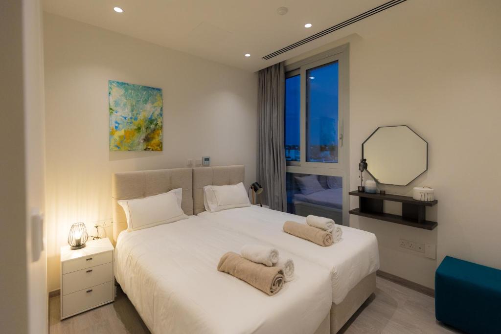 1 dormitorio con 1 cama blanca grande y toallas. en Napa Hills Seaview Villas, en Ayia Napa
