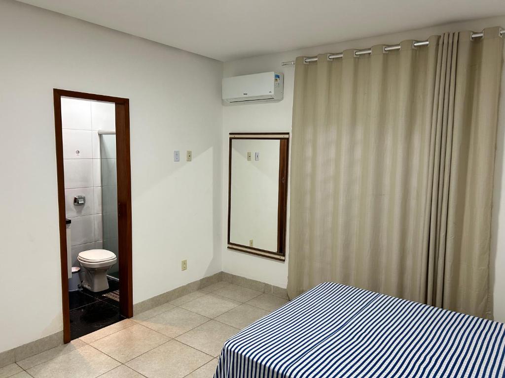 a bedroom with a bed and a bathroom with a toilet at Ap barato e perfeito insta thiagojacomo in Goiânia