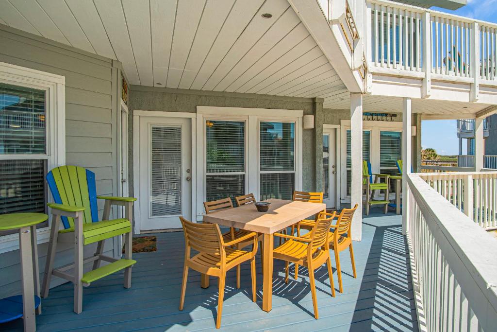 un porche con mesa y sillas en una casa en Smiling Jacks Escape Condominium, en Mustang Beach