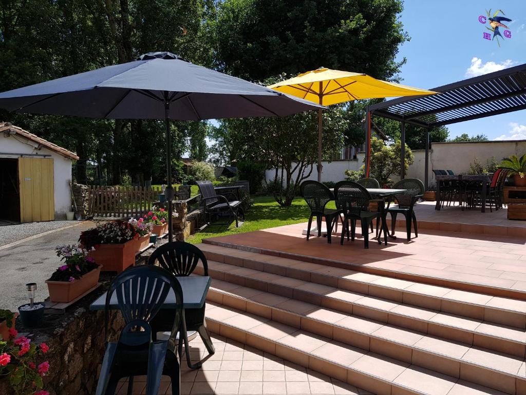 a patio with tables and chairs and umbrellas at Chambre d'Hôtes le Gachignard in Courlay