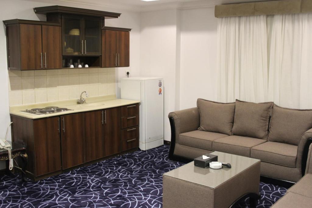een woonkamer met een bank en een keuken bij Carawan Al Khaleej Hotel Olaya in Riyad