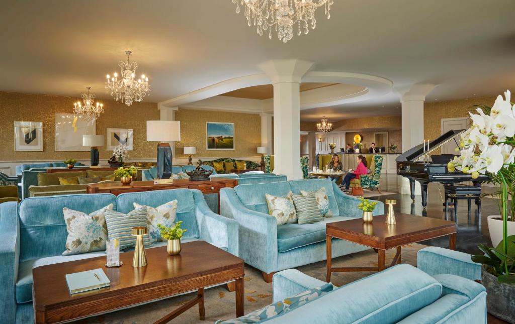 a living room with blue couches and a piano at Newpark Hotel in Kilkenny