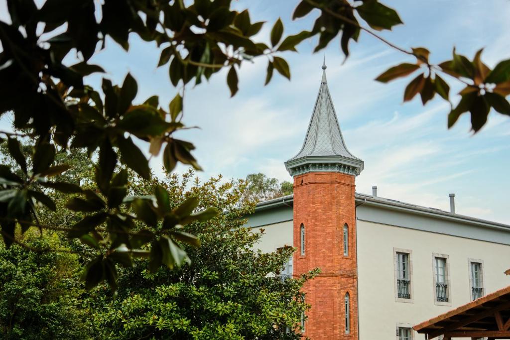 uma torre de tijolos no topo de um edifício em HOTEL BOUTIQUE VILLA DEL MARQUÉS em Muros de Nalón