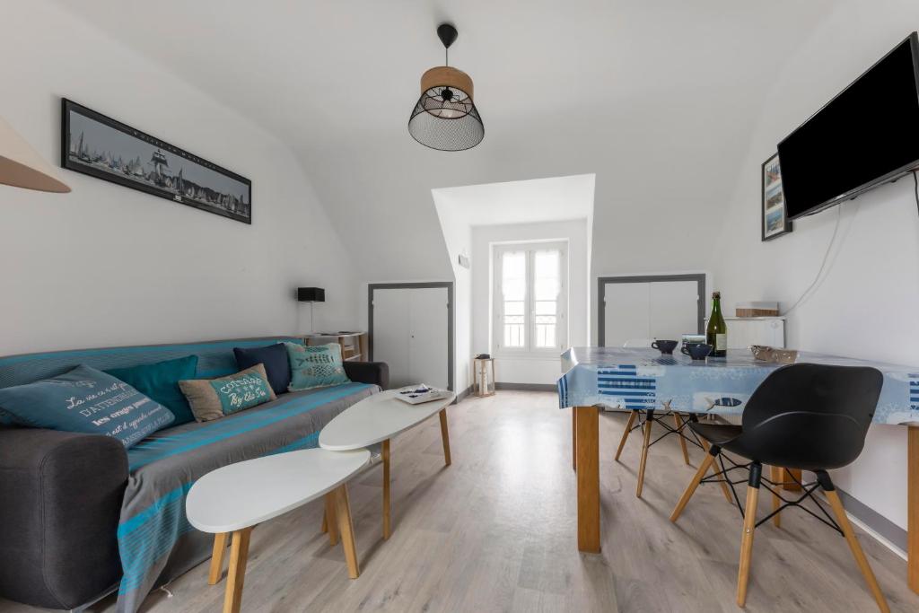 ein Wohnzimmer mit einem blauen Sofa und einem Tisch in der Unterkunft Chez Merlin in Larmor-Baden
