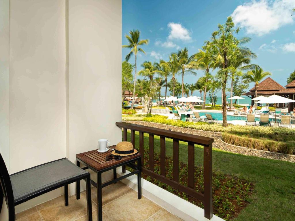 a balcony with a table and a bench and a pool at Hotel Ibis Samui Bophut in Bophut