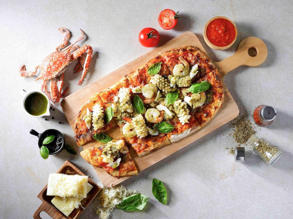 a pizza on a cutting board on a table at Hotel Ibis Samui Bophut in Bophut