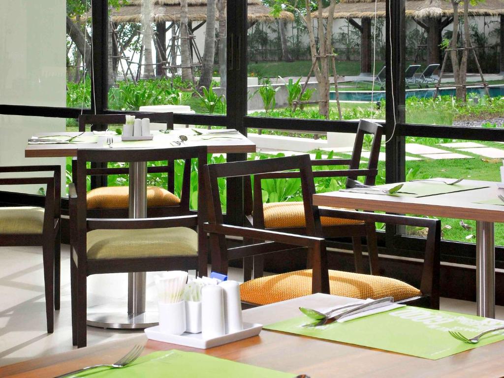 a dining room with tables and chairs and a window at Hotel Ibis Samui Bophut in Bophut