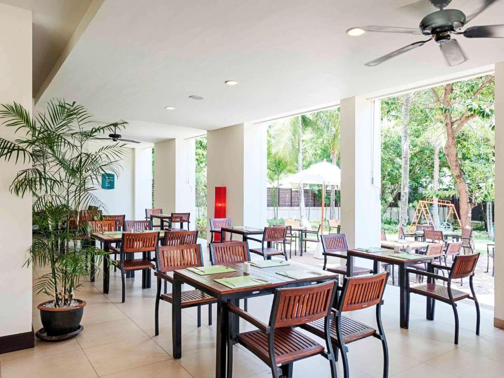 a restaurant with tables and chairs and a ceiling fan at Hotel Ibis Samui Bophut in Bophut