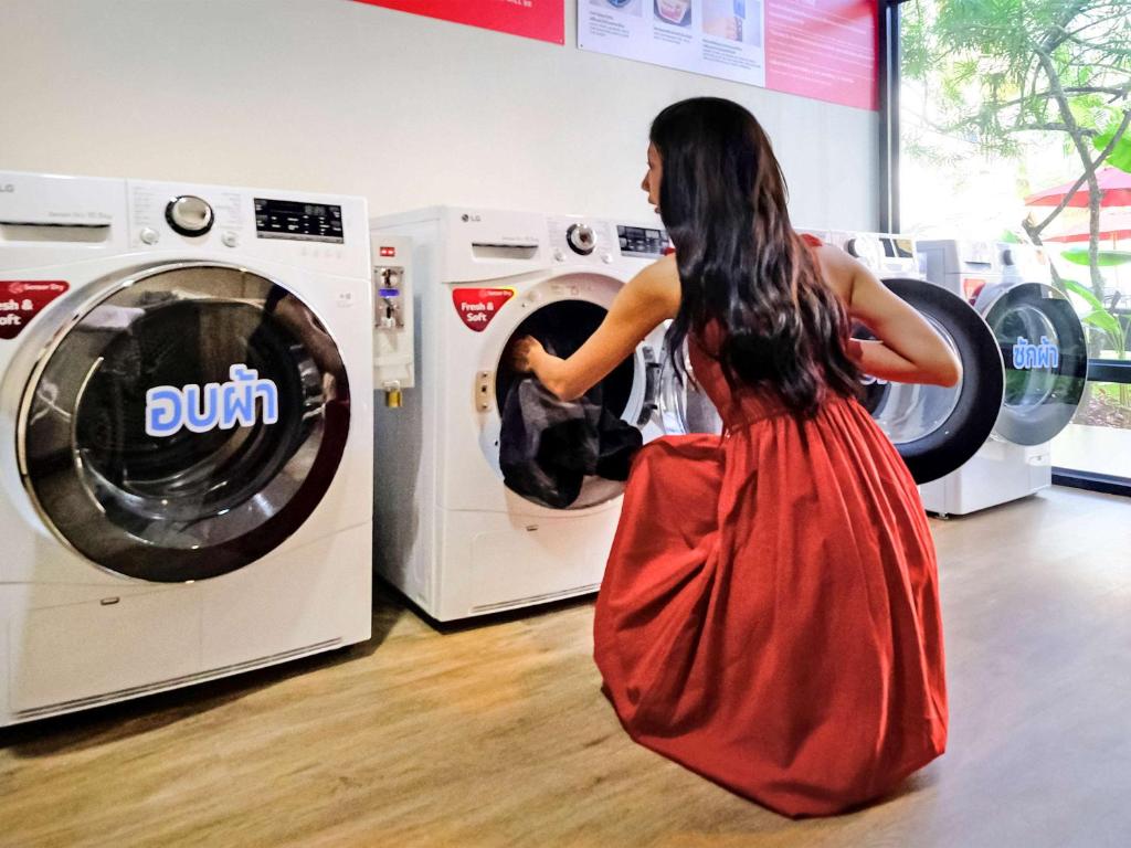 a woman in a red dress standing in front of a washing machine at Hotel Ibis Samui Bophut in Bophut