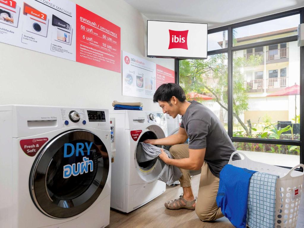 a man is washing a washing machine in a store at Hotel Ibis Samui Bophut in Bophut
