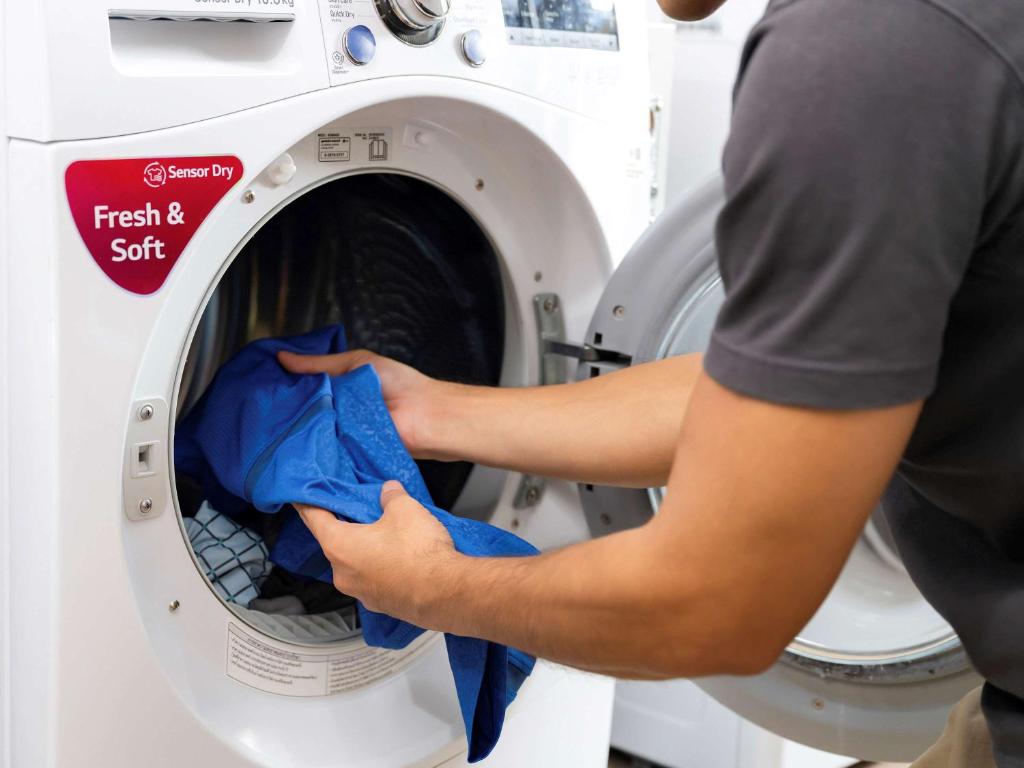 a person putting a cloth into a washing machine at Hotel Ibis Samui Bophut in Bophut