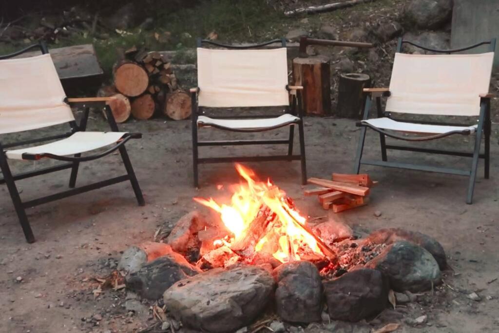 a fire pit with two chairs and a campfire at 一軒家貸切 ARUYOguesthouse BBQと焚き火ができる宿 