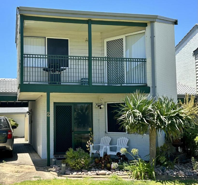 a house with a balcony and two white chairs at Beachside Townhouse Bunbury in Bunbury
