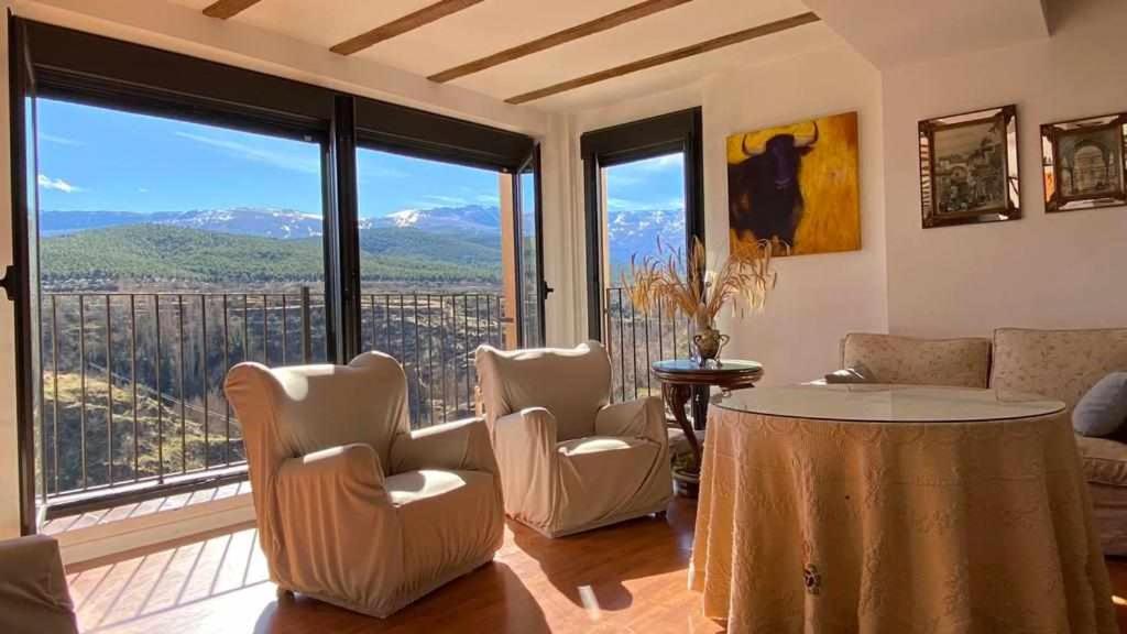 sala de estar con sillas, mesa y ventanas grandes en Casona Torre de Alcázar en Jerez del Marquesado