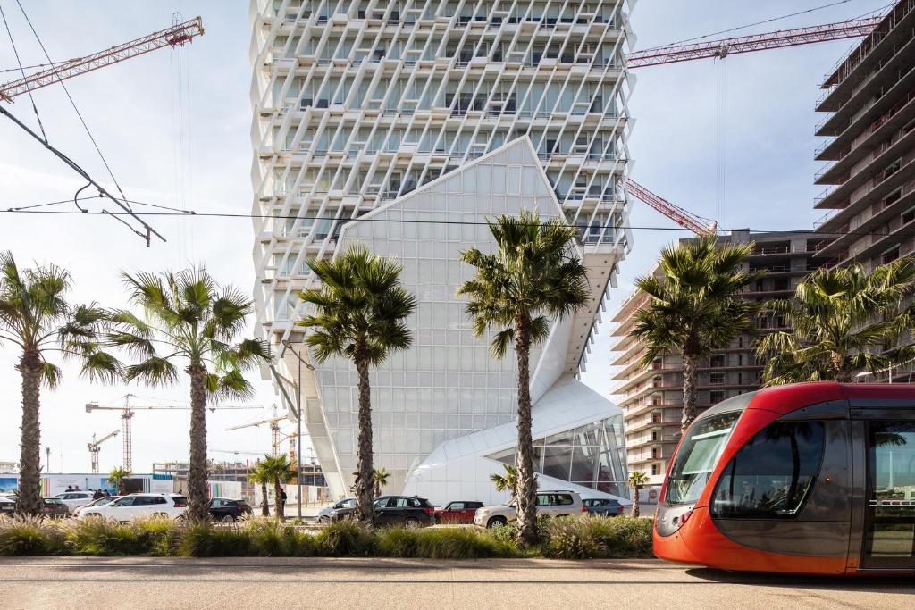 a red tram in front of a tall building with palm trees at Residence Boule d'OR- EMPLACEMENT - NETFLIX - FREE PARKING in Casablanca