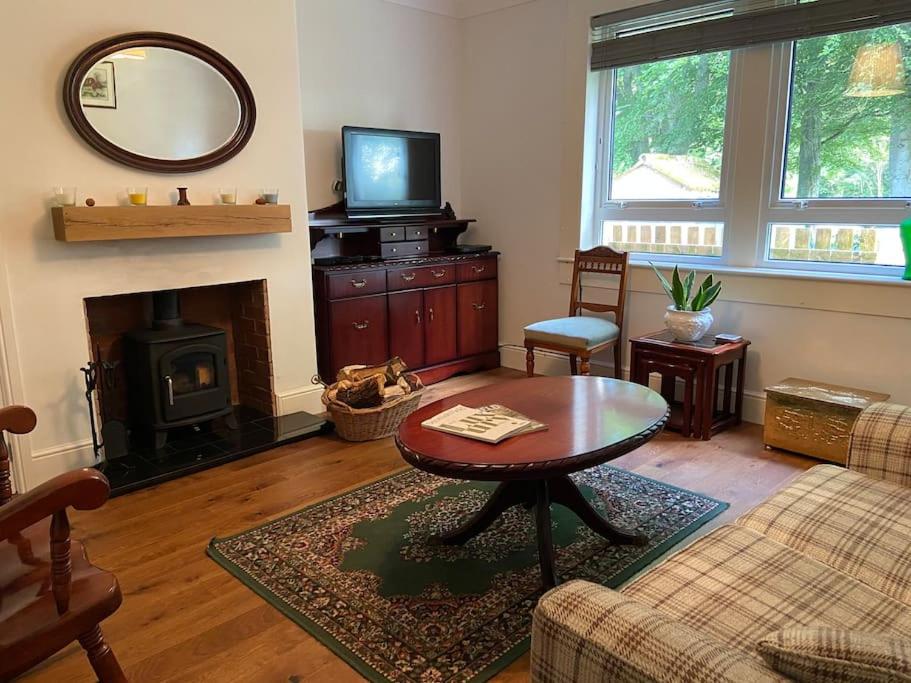 a living room with a table and a fireplace at Lovely little house in Yarrowford - Yarrow Valley in Broadmeadows