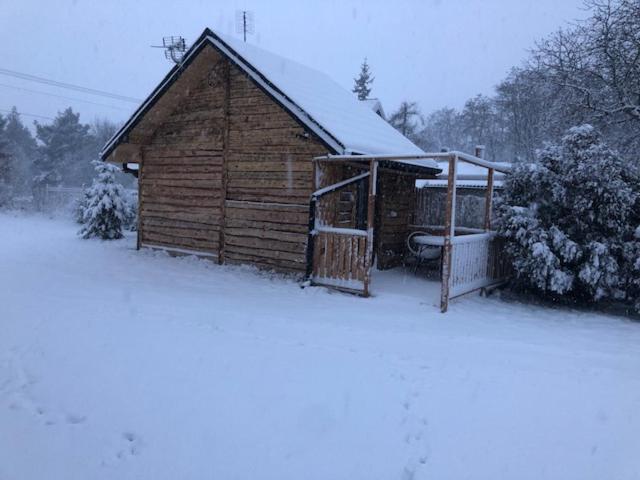 Cabaña de madera con nieve en el suelo en Domek dla par agroturystyka siedlisko, 