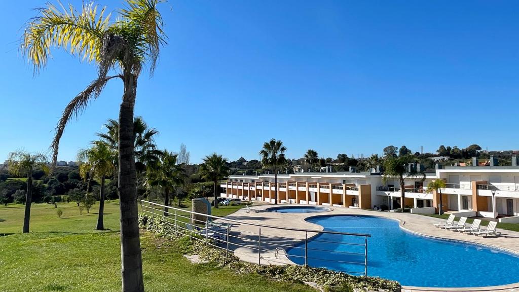a view of a resort with a swimming pool and a palm tree at White by Check-in Portugal in Albufeira