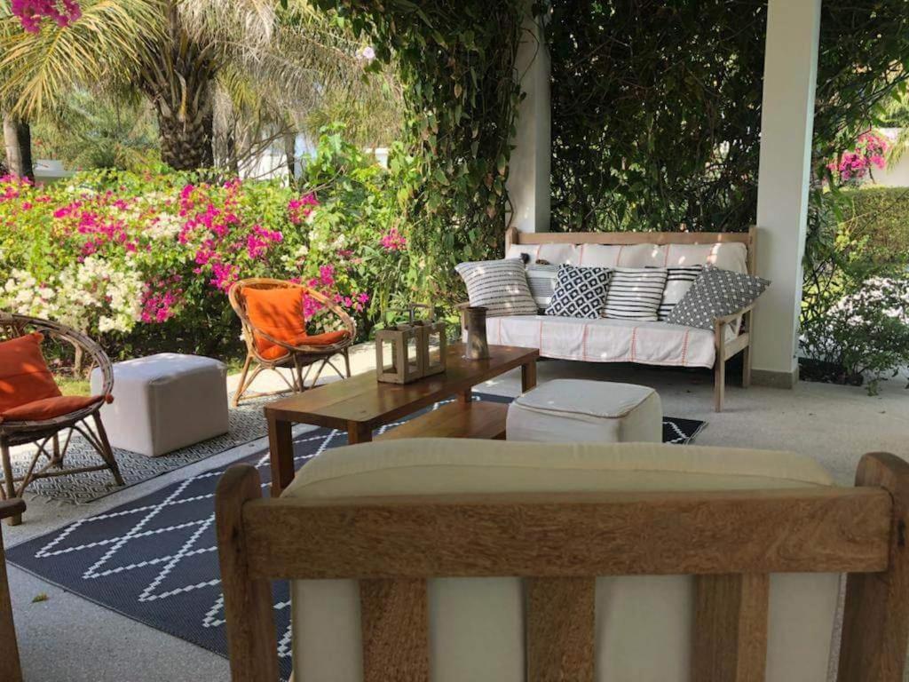 a patio with a couch and tables and chairs at Villa CITRONS VERTS dans un parc arboré vue mer in Cap Skirring