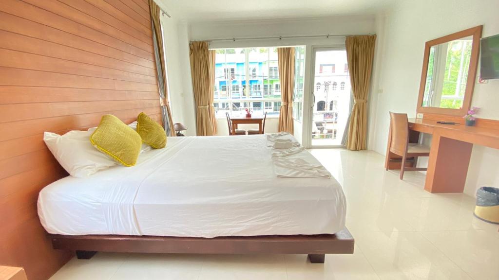 a bedroom with a large white bed with yellow pillows at Sukcheewa Residence Phuket in Patong Beach