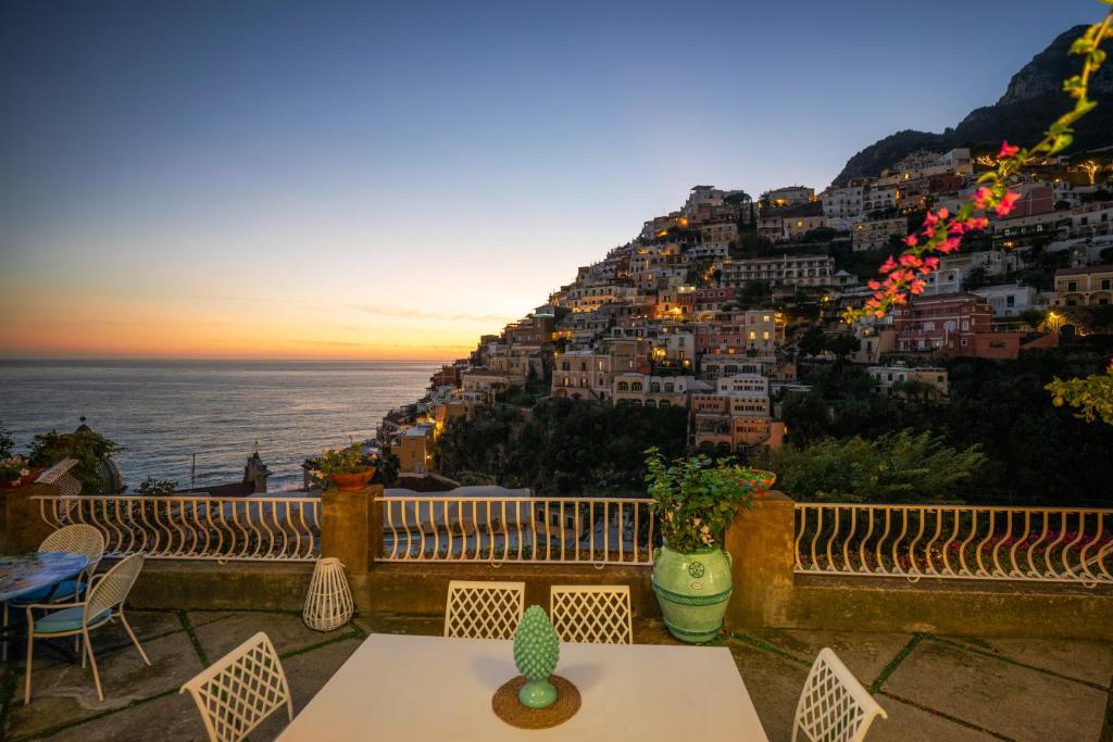 a balcony with a table and chairs and a mountain at Villa Dalu in Positano