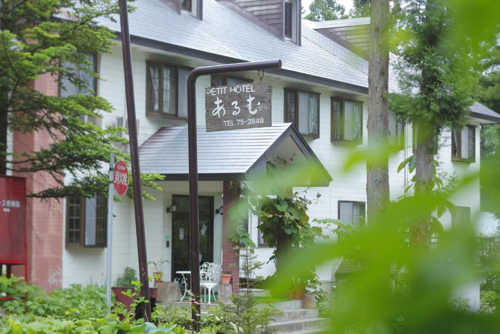 un letrero de la calle frente a una casa blanca en HakubaGoryu Pension&LogCottage Arumu, en Hakuba