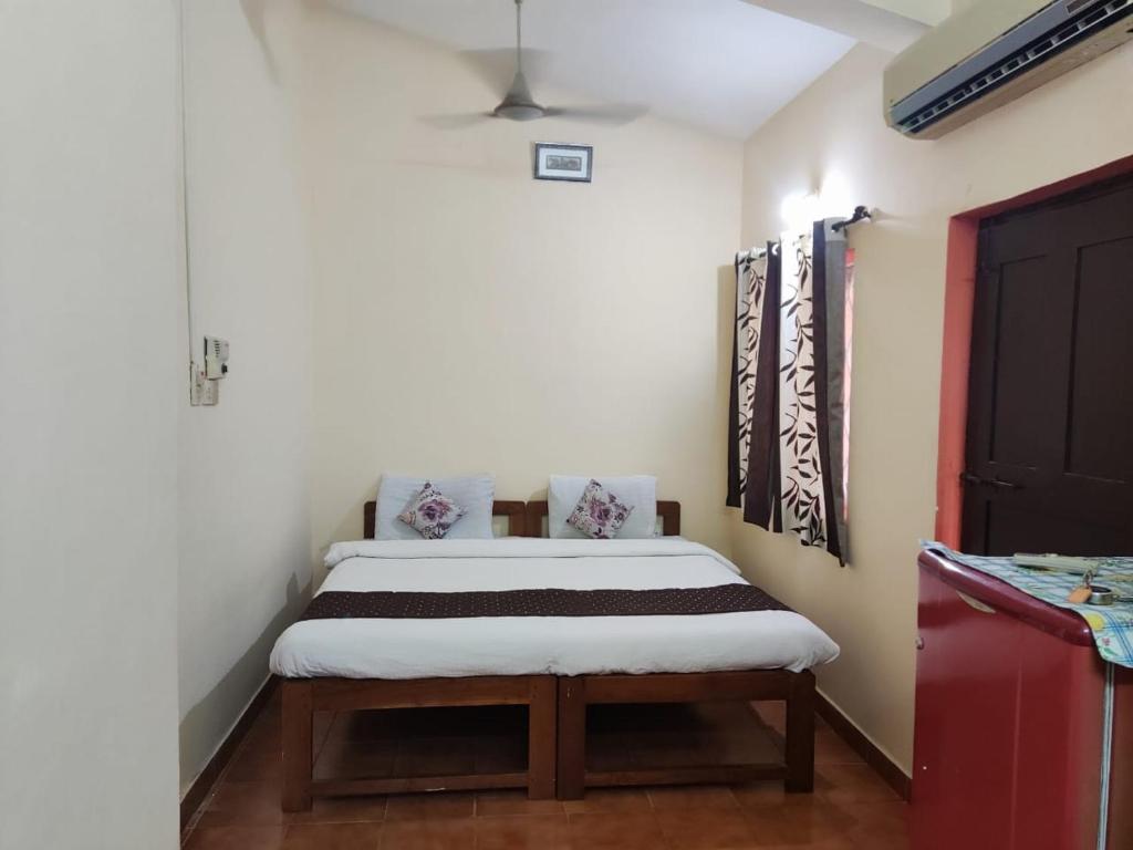 a small bedroom with a bed in a room at Camrose Guest House in Candolim