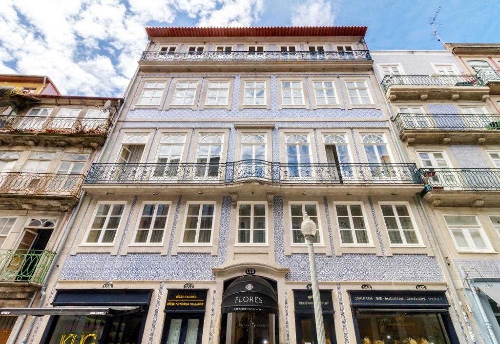 a tall building with windows and balconies on a street at Oca Flores Hotel Boutique in Porto