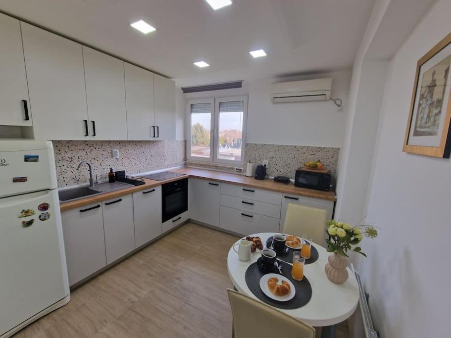 a kitchen with white cabinets and a table with food on it at Studio SVACIC self check in in Osijek