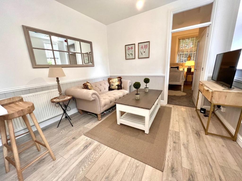 a living room with a couch and a piano at Rose Cottage at The Stables in Stannington