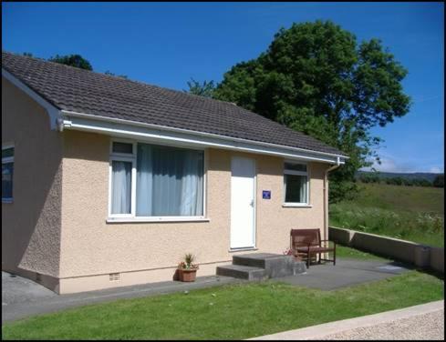 a small house with a bench in front of it at Glen Dhoo Country Cottages - Meadowview Bungalow in Onchan