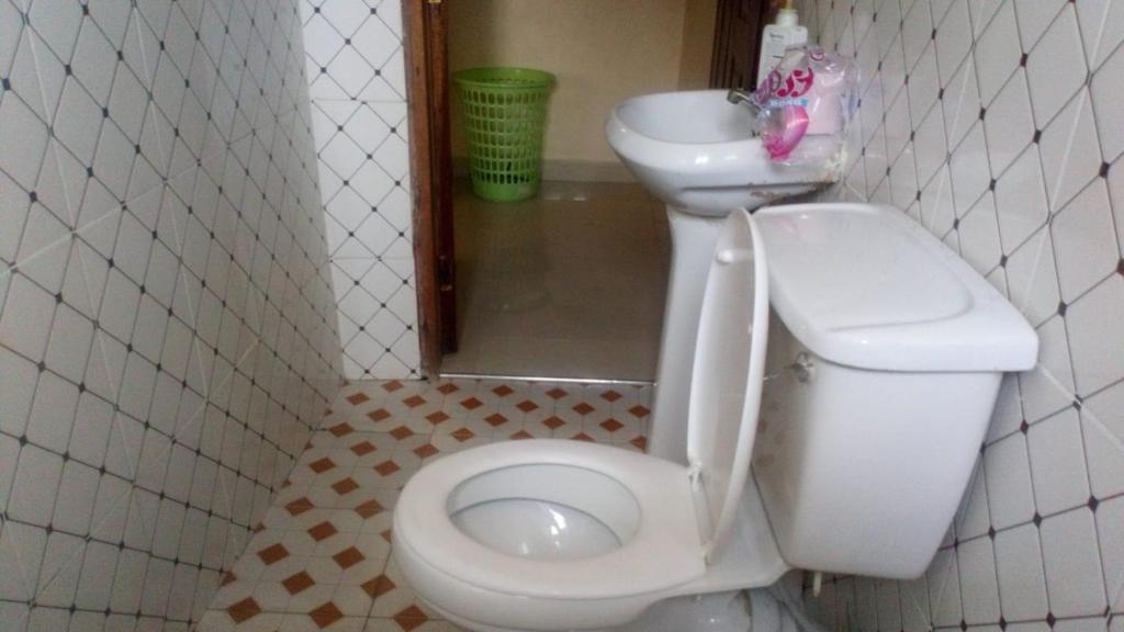 a bathroom with a white toilet and a sink at KITWE PEMBENI APARTMENTS in Mombasa