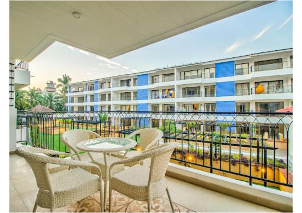 een balkon met een tafel en stoelen en een gebouw bij Telferk Acron Seawinds Apartment- Baga in Calangute