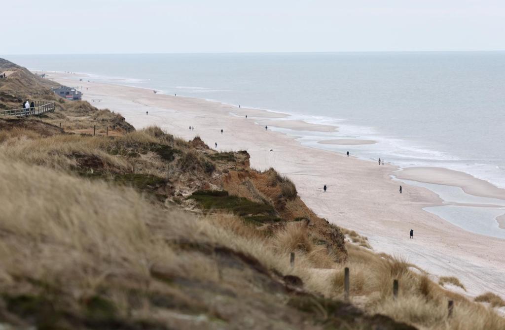 eine Gruppe von Menschen, die am Strand spazieren gehen in der Unterkunft Ruarklef in Kampen