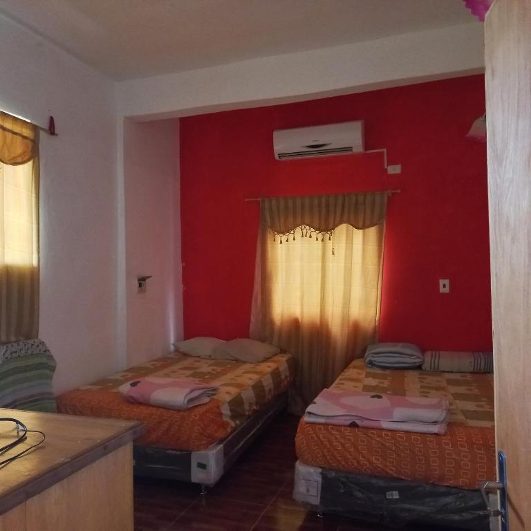 a room with two beds and a red wall at Hospedaje por día.. in Encarnación