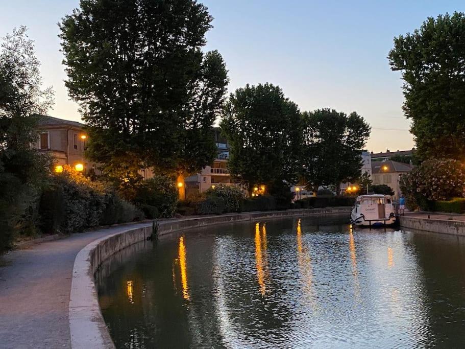 une rivière avec des lumières réfléchissant dans l'eau la nuit dans l'établissement Dupleix au Fil du Canal, à Narbonne