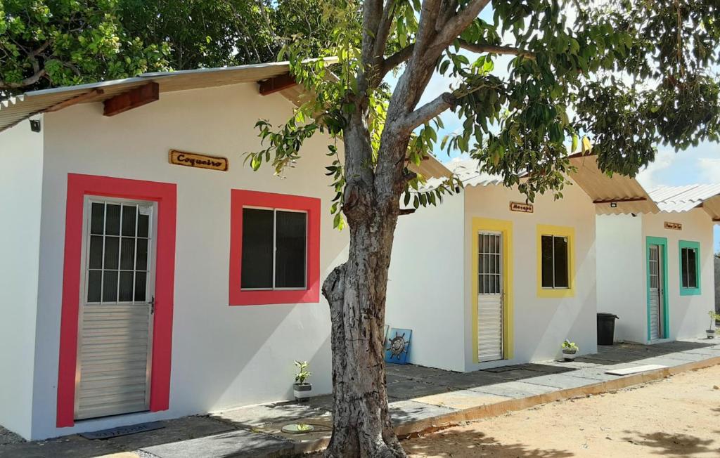 a building with colorful doors and a tree at Chales do delta Piauí in Parnaíba