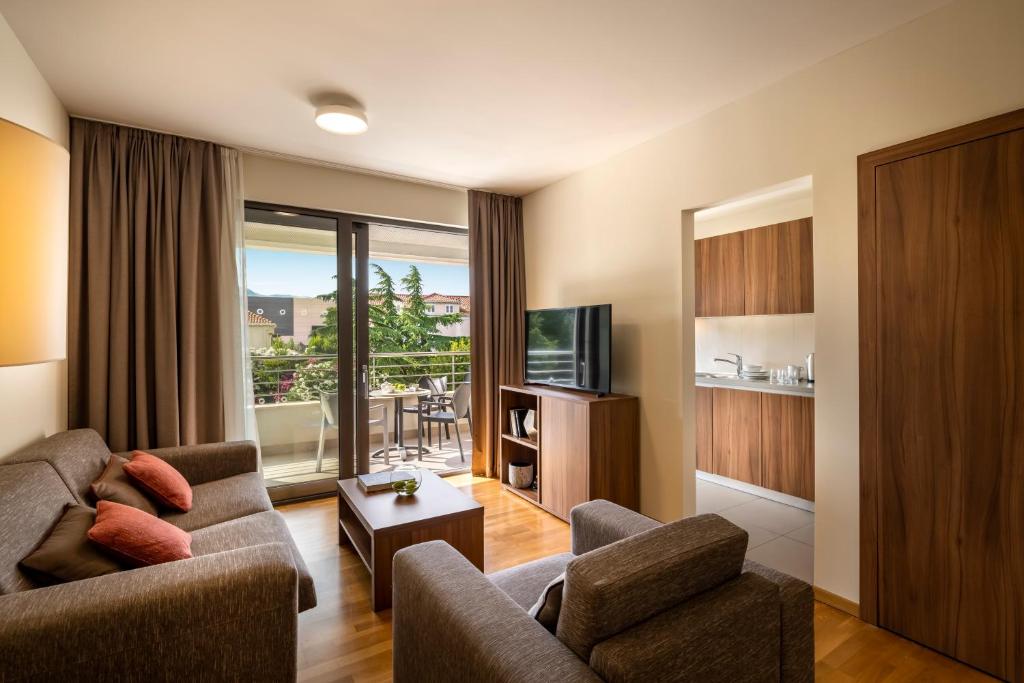 a living room with a couch and a tv at Maistra Select Srebreno Premium Apartments in Srebreno