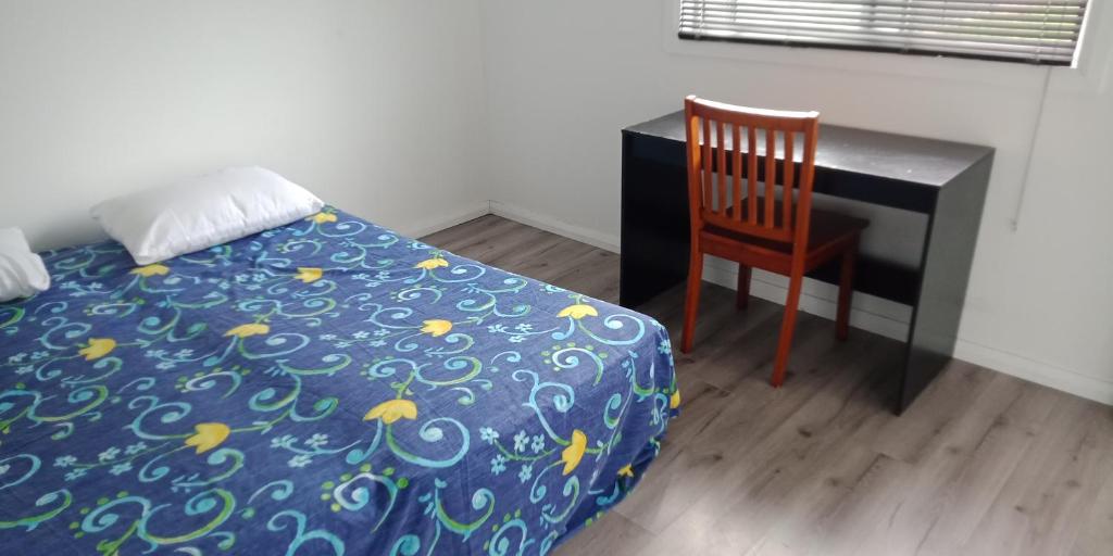 1 dormitorio con cama, escritorio y silla en Simple room en Riverwood