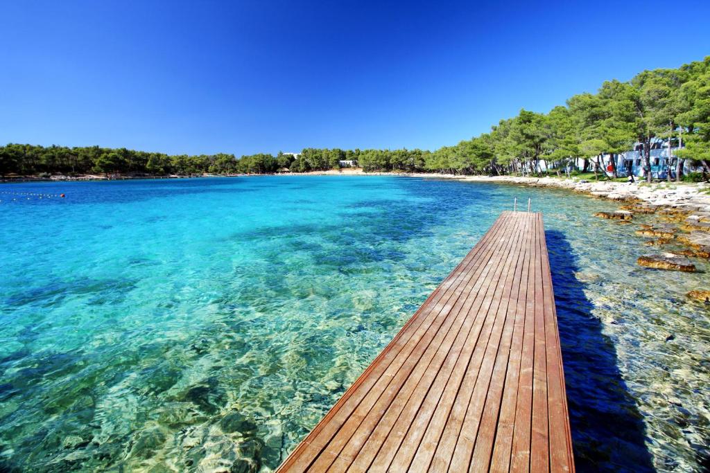 un camino de madera sobre el agua en una playa en Crvena Luka Resort, en Biograd na Moru