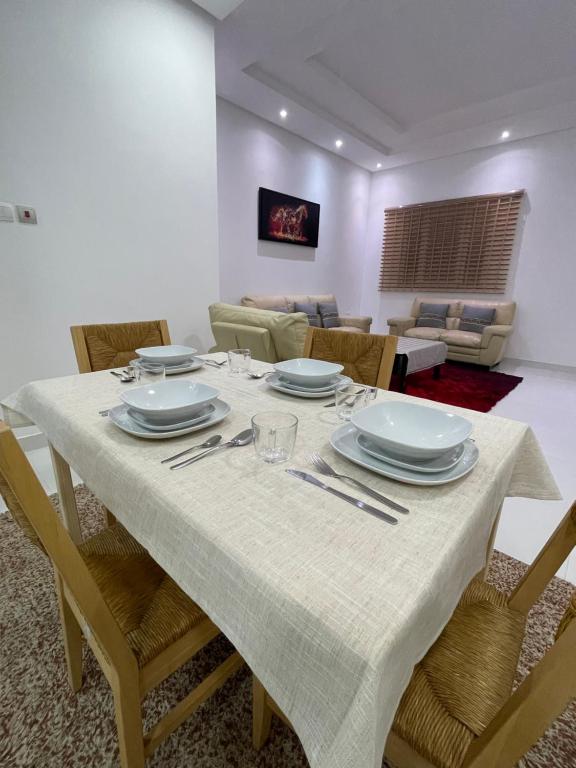 a dining room with a table with plates and silverware at Al Qalah flats 