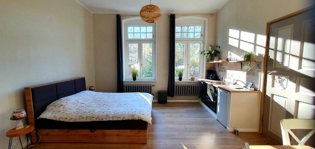 a bedroom with a bed and a kitchen with windows at Vogtlandperle in Oelsnitz/Vogtland
