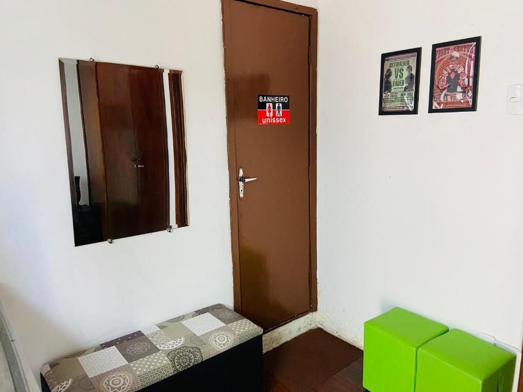 a small room with a door and a green stool at Rota BH Hostel in Belo Horizonte
