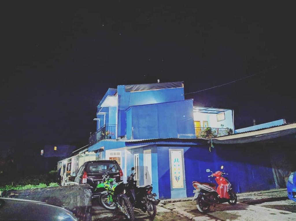 zwei Motorräder, die nachts vor einem blauen Gebäude geparkt werden in der Unterkunft Homestay Ulya 2 in Diyeng