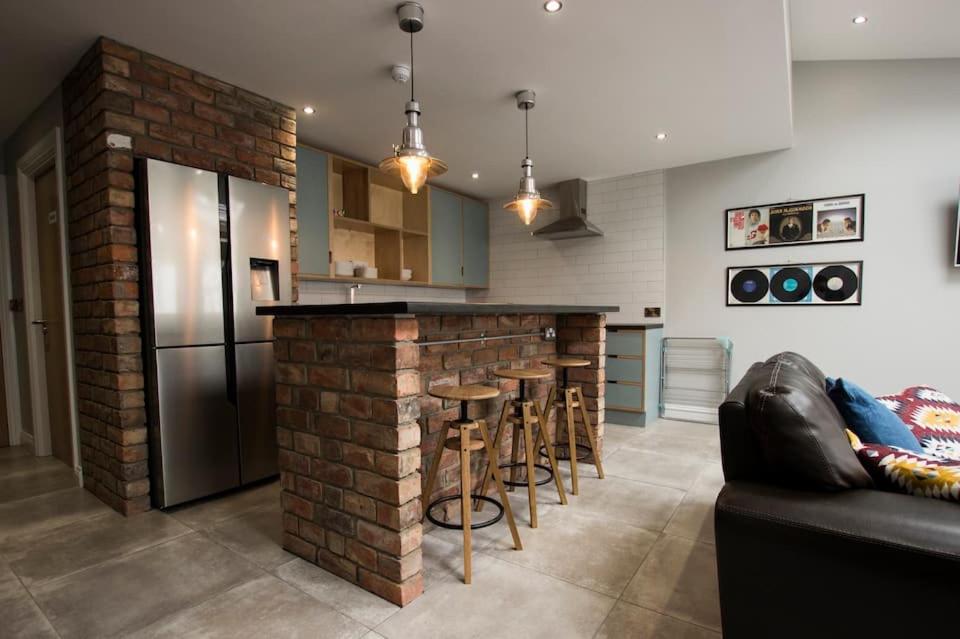 cocina con barra de ladrillo con taburetes y nevera en Modern City Centre Rooms, en Dublín