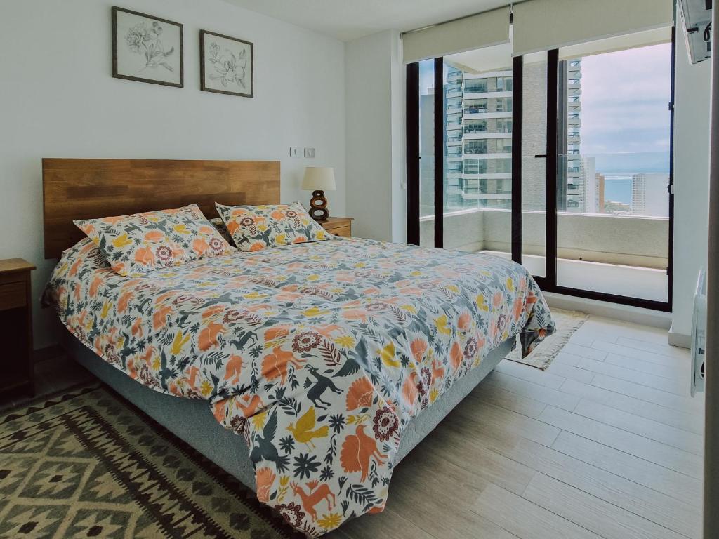a bedroom with a bed with a colorful comforter at Departamento en Costas de Montemar, a pasos de la playa, con Vista al Mar, Piscina y GYM in Valparaíso